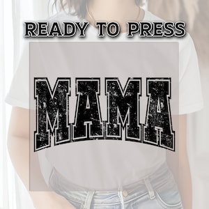 May include: A white t-shirt with the word "MAMA" printed in black with a distressed, vintage-style font.