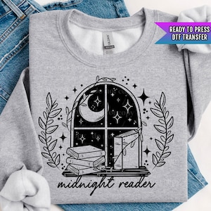 May include: A black and white graphic design of a window with a crescent moon and stars, a stack of books, and the text "midnight reader".