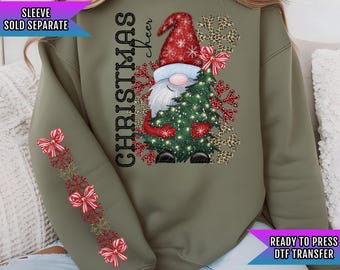 Könnte beinhalten: Grüner Pullover mit einem Weihnachtszwerg, der einen Weihnachtsbaum hält. Der Zwerg trägt eine rote Mütze mit weißen Schneeflocken. Der Text "Christmas Cheer" ist auf dem Pullover aufgedruckt. Die Ärmel haben ein rotes und weißes Schleifenmuster.