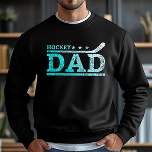 May include: Black sweatshirt with a blue and white graphic that says "Hockey Dad" with three stars and a hockey stick.