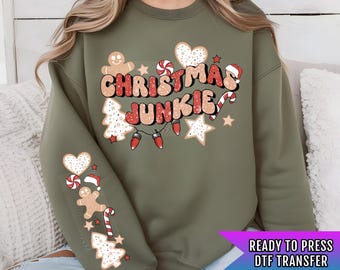 May include: Green sweatshirt with a Christmas Junkie design. The design features a gingerbread man, candy canes, stars, hearts, and lights. The text is in a retro font.