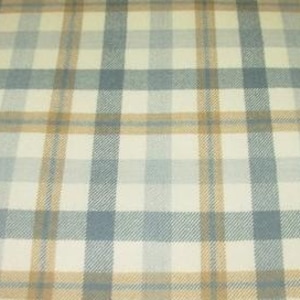 May include: A woven fabric featuring a plaid pattern with intersecting lines in shades of light blue, tan, and cream. The textile displays a consistent grid design with alternating vertical and horizontal stripes that create a classic checkered appearance.