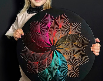 May include: A circular string art piece with a black background. The string art is made of different colours of thread, including red, orange, yellow, green, blue, and purple. The string art is arranged in a spiral pattern, creating a visually appealing design.