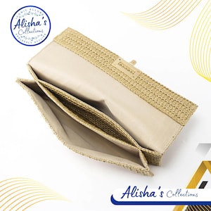 Pode incluir: Uma carteira de m&atilde;o tecida bege com fecho de aba e fecho de metal dourado. A carteira est&aacute; aberta e o interior &eacute; forrado com um tecido bege.