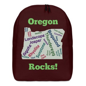 May include: A maroon backpack with a green outline of the state of Oregon and the words "Oregon Rocks!" in green. The outline of the state is filled with a word cloud of different types of rocks found in Oregon, including agate, jasper, obsidian, rhyolite, and sunstone.
