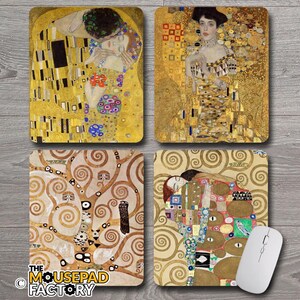 May include: Four rectangular mousepads featuring artwork by Gustav Klimt. The mousepads showcase different paintings, including "The Kiss" and portraits, with gold and earth-tone color palettes. A white computer mouse is placed on one of the mousepads.