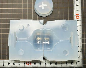 May include: A light blue silicone wine glass mould, split into two halves, with a matching lid. The mould features a detailed design of a wine glass shape. The ruler shows measurements in centimetres.