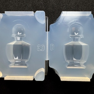 May include: Two-part, clear silicone mould for crafting a decorative bottle. The mould features a detailed design of a classic perfume bottle shape. The number "30" is visible on the mould. The mould is designed for creating resin or other craft projects.