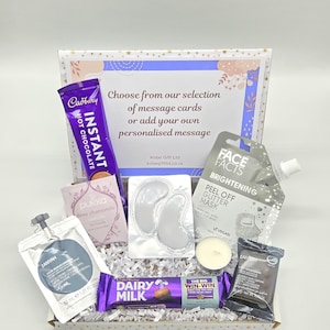 May include: A gift box containing a selection of treats, including Cadbury Instant Hot Chocolate, a face mask, eye patches, and a Dairy Milk chocolate bar. Also included is a candle and a message card.