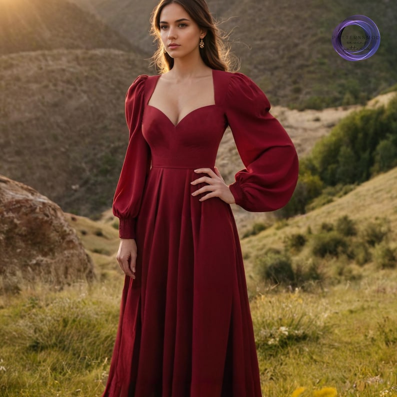 K&ouml;nnte beinhalten: Ein bordeauxfarbenes Abendkleid mit quadratischem Ausschnitt und langen, volumin&ouml;sen &Auml;rmeln. Das Kleid hat ein figurbetontes Oberteil und einen flie&szlig;enden Rock. Das Model steht im Freien vor einer Bergkulisse. Geeignet f&uuml;r besondere Anl&auml;sse.