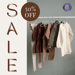 May include: Sale sign with 50% off text. Five brown and beige clothing items hang on a white rack against a gray background.