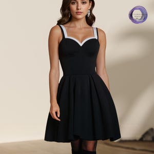 Peut inclure: Une robe patineuse noire avec une bordure blanche autour de l'encolure. La robe a une encolure en c&oelig;ur et un corsage ajust&eacute;. La jupe est ample et s'&eacute;vase &agrave; partir de la taille.