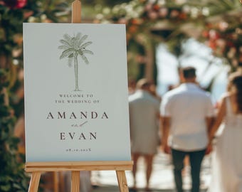 May include: A white welcome sign with a green palm tree illustration. The sign reads "Welcome to the wedding of Amanda and Evan 08.10.202X".