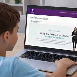 May include: A young person is using a laptop displaying a website titled "Student Success Coach." The screen shows text that reads "Build the habits that lead to academic success." A woman in a black suit is also visible on the screen.