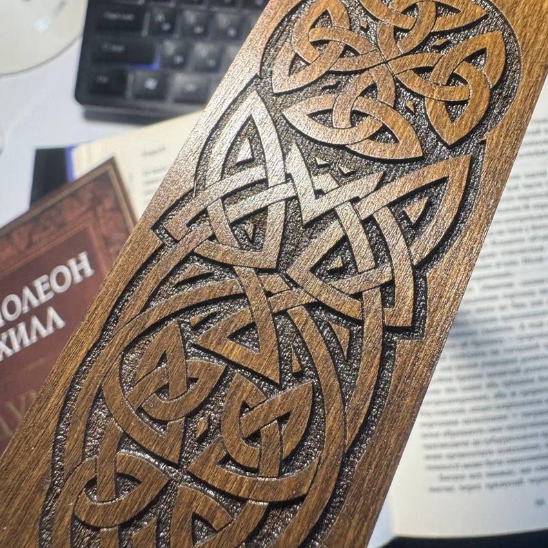 Pu&ograve; includere: Un segnalibro in legno con un dettagliato disegno a nodo celtico. Il segnalibro &egrave; di colore marrone caldo, con l'intricato motivo intagliato nel legno. Il design presenta linee e forme intrecciate, creando un motivo complesso e visivamente accattivante. Il segnalibro &egrave; rettangolare.