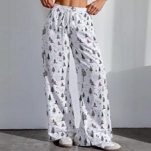 May include: White pajama trousers featuring a repeating pattern of skiers, trees, and dots. The trousers have a drawstring waist and a wide-leg design. The skiers are in red and black, and the trees are green and brown.