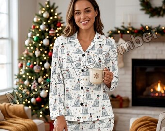 May include: A white long-sleeve button-down pajama top and matching pants featuring a repeating pattern of dalmatian dogs wearing red scarves, interspersed with small gold snowflakes. The shirt has a notched collar and black buttons.