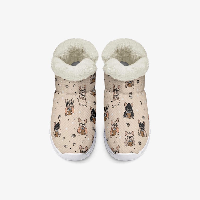 May include: A pair of beige indoor slippers with a repeating pattern of French bulldogs holding coffee cups. The slippers have a white sole and a fluffy, cream-colored lining around the ankle.
