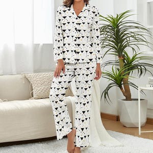 Può includere: Pigiama bianco con motivo a bicchieri da martini neri e oro. La parte superiore a maniche lunghe ha un colletto e una chiusura con bottoni. I pantaloni sono a gamba dritta. Il pigiama è realizzato in un materiale morbido e confortevole.