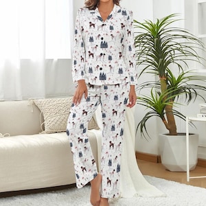 May include: White pajama set with a repeating pattern of brown dogs and blue Christmas trees. The long-sleeved top has a button-down front and a notched collar. The pants are straight-legged. The pajamas are made of a soft, comfortable material.