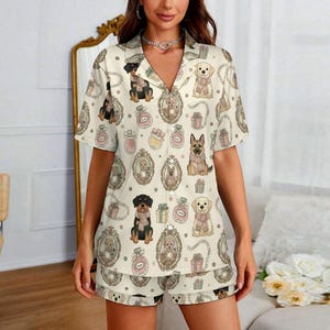 Può includere: Pigiama color crema con un motivo ripetuto di varie razze di cani in cornici decorative, flaconi di profumo e scatole regalo. La maglia a maniche corte e i pantaloncini sono in tessuto morbido. I cani indossano sciarpe.