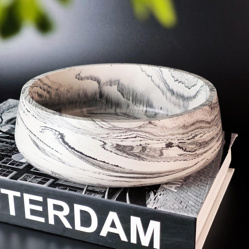 Side profile of a thick-walled monochrome decorative dish showing the seamless transition of black and white waves.
