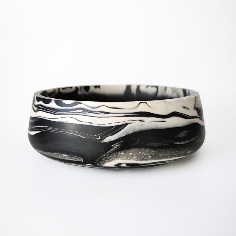 A black and white marbled ceramic bowl. The bowl has a wide, rounded base and a slightly flared rim.