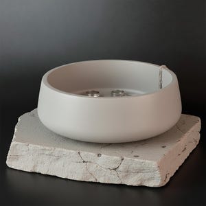 Modern gray stone-smooth bowl styled as an entryway key holder on a light oak wood surface.