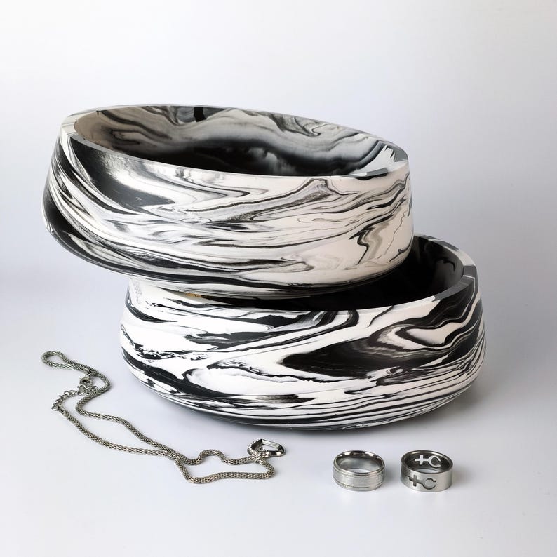 Close-up of a black and white marbled decorative bowl showing fluid organic swirls and a smooth stone-like finish.