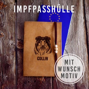 Op de afbeelding: Een bruinleren paspoorthouder met een hondenillustratie en de naam "COLLIN" wordt getoond op een houten oppervlak. Een blauw paspoort en een decoratief label zijn ook zichtbaar. De tekst "IMPFPASSHÜLLE" staat bovenaan.