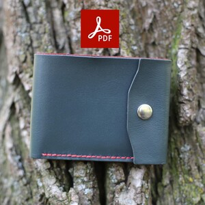 May include: A dark blue leather wallet with a red stitch detail and a silver button closure. The wallet is sitting on a tree trunk.
