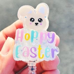 May include: A glittery white bunny-shaped badge reel with the words "Happy Easter" in pastel colours. The badge reel has a clear plastic retractable cord and a clip for attaching to clothing.