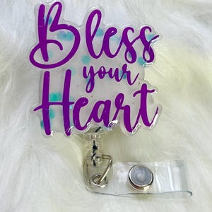May include: A clear plastic badge holder with a purple glitter design that says "Bless your Heart".