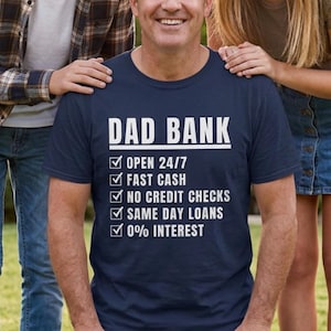 Könnte beinhalten: Marineblaues T-Shirt mit weißem Text "DAD BANK". Darunter befinden sich Kontrollkästchen mit den Phrasen "OPEN 24/7", "FAST CASH", "NO CREDIT CHECKS", "SAME DAY LOANS" und "0% INTEREST".