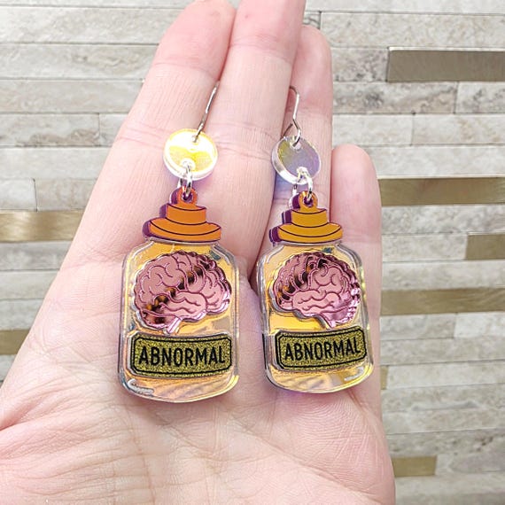 Handmade acrylic earrings shaped like apothecary jars filled with an 'abnormal brain' — a wearable nod to Frankenstein lab aesthetics that doubles as a conversation starter.