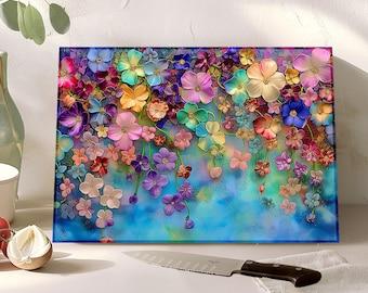 May include: A colourful glass chopping board with a floral design. The flowers are in shades of pink, purple, blue, and yellow. The background is a light blue with a subtle sparkle.
