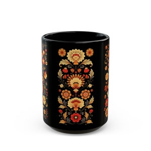 May include: Black ceramic mug with a floral pattern in shades of orange, yellow, and red. The pattern features stylized flowers and leaves.