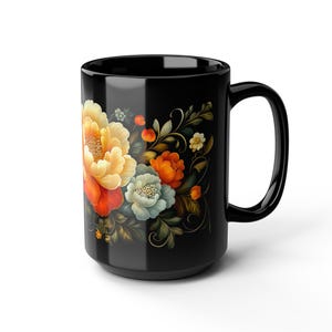 May include: Black ceramic mug featuring a floral design with yellow, orange, and blue flowers. The flowers are set against a black background, with green leaves and stems. The mug has a large handle.