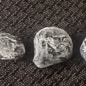 May include: Five smooth, gray stones with white markings. The stones are oval-shaped and have a natural, polished look.
