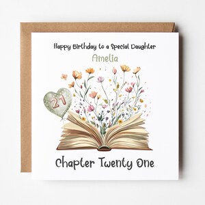 May include: A white card with a brown envelope. The card has a floral design with an open book and a heart-shaped balloon with the number 21. The text on the card reads "Happy Birthday to a Special Daughter Amelia Chapter Twenty One".