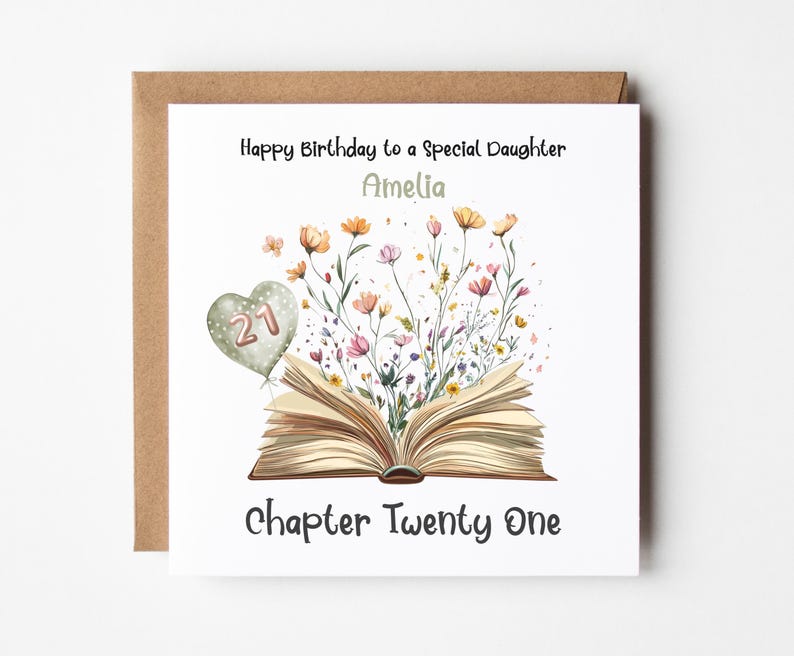 May include: A white card with a brown envelope. The card has a floral design with an open book and a heart-shaped balloon with the number 21. The text on the card reads "Happy Birthday to a Special Daughter Amelia Chapter Twenty One".