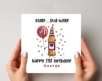 May include: A birthday card held by hands features a cartoon beer bottle wearing a party hat and holding a red balloon with the number 21. The card reads "older...bud-wiser" and "happy 21st birthday!" with the name "George" below.