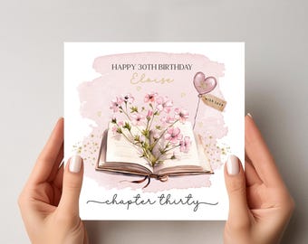 Puede incluir: Tarjeta de cumpleaños con el texto "Happy 30th Birthday Eloise" y "chapter thirty". La tarjeta presenta un libro abierto con flores rosas, un globo en forma de corazón y una etiqueta que dice "with love". El fondo es un lavado de acuarela rosa suave.