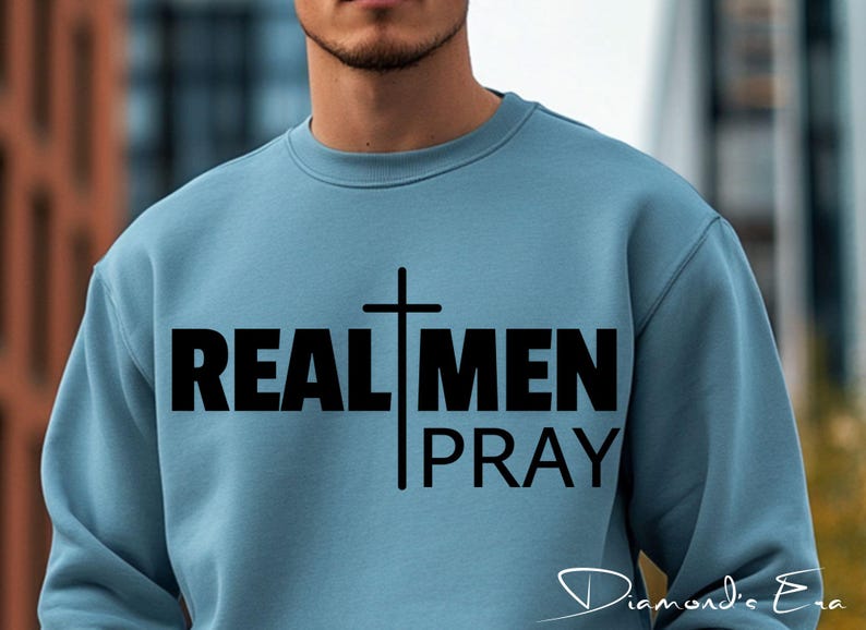 May include: A light blue sweatshirt with a black cross and the text "REAL MEN PRAY" printed on the front.