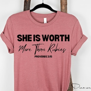 May include: A pink t-shirt with the text "She is worth more than rubies" and "Proverbs 3:15" in black.