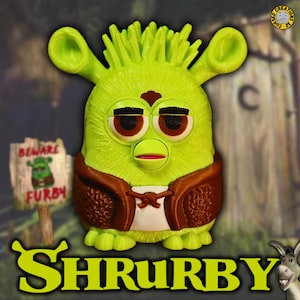 Op de afbeelding: Een groen Shrek-thema Furby-speelgoed met bruine accenten, met een bruin vest en een wit shirt. Het woord "SHRUBBY" staat onderaan, met een bord met de tekst "BEWARE FURBY".