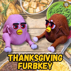 May include: Two novelty toys, a pink and a brown Furby-turkey hybrid, are displayed on a wooden surface. The toys have large eyes, yellow beaks, and white feet. The text "THANKSGIVING FURBKEY" is in yellow block letters.