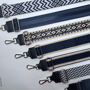Könnte beinhalten: Fünf verschiedene schwarz-weiße gemusterte Riemen mit silberner Hardware. Die Riemen sind aus Stoff und haben ein gewebtes Design.