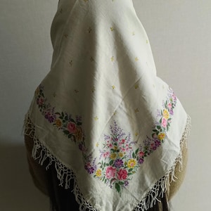 Puede incluir: Un pañuelo de algodón blanco con un patrón floral y una franja de ganchillo. El pañuelo tiene un pequeño patrón de puntos amarillos en toda su superficie.