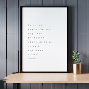May include: Black and white typography print with a quote by Ralph Waldo Emerson: "Do not go where the path may lead, go instead where there is no path and leave a trail."